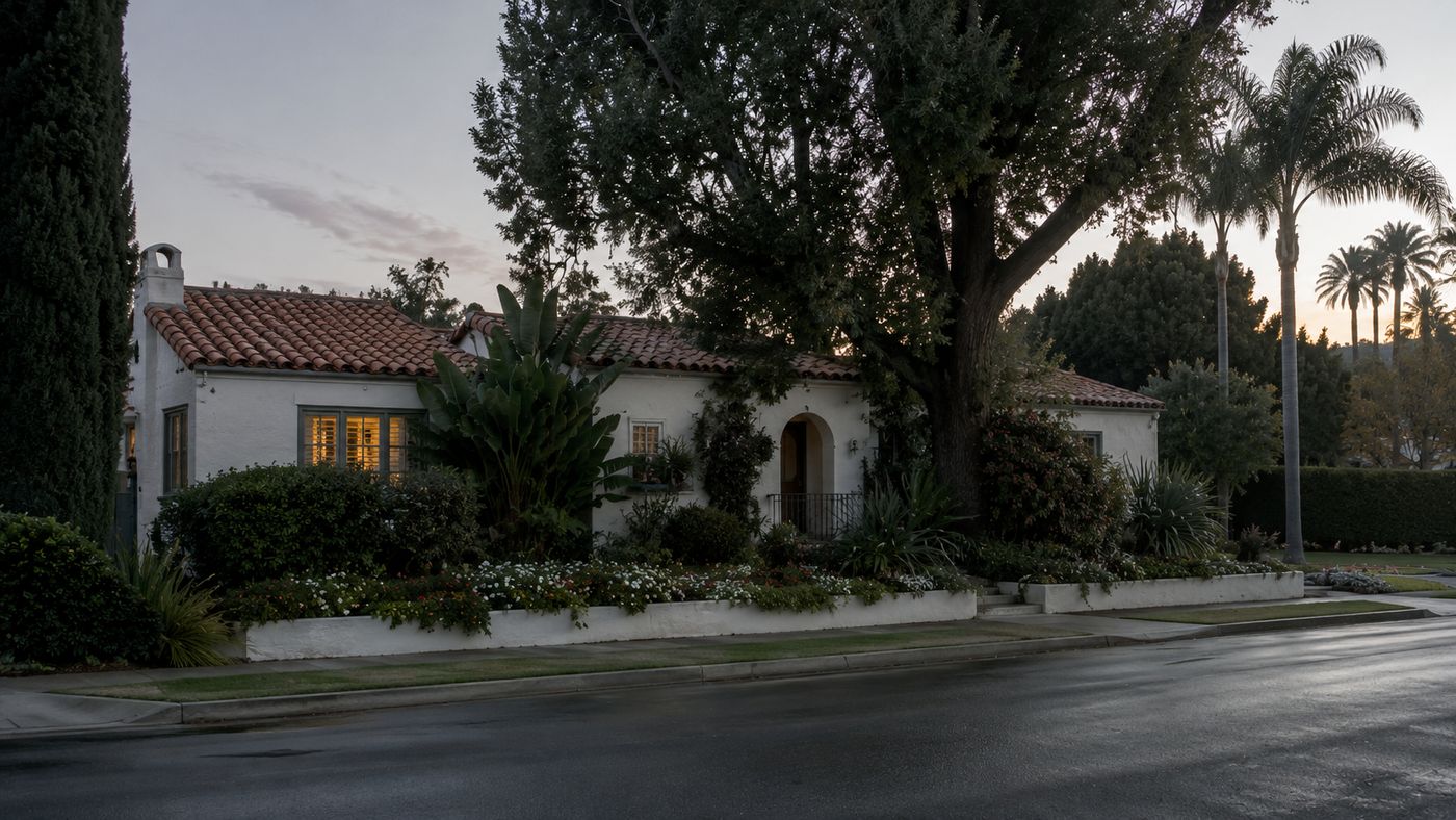 A modest Spanish-style bungalow in a quiet Los Angeles neighborhood, surrounded by gardens, the exterior peaceful in early morning light