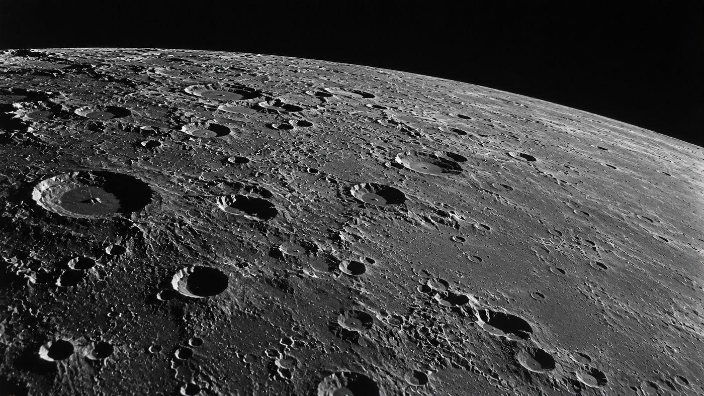 A close-up view of the lunar surface showing a field of craters in varying sizes, the gray terrain illuminated by sharp angular sunlight against black space